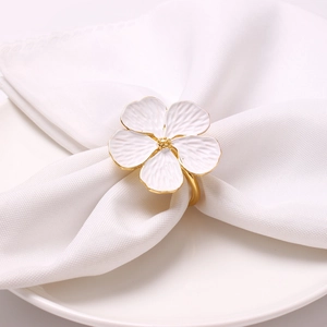 Elegant white floral napkin ring with gold edges on white fabric for table setting