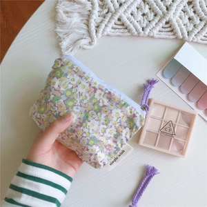 Gros plan d'une pochette en coton à fleurs lilas pour monnaie et rouge à lèvres avec étiquette