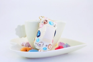 Close-up of car-shaped keychain with colorful gemstones and rhinestones in a cup
