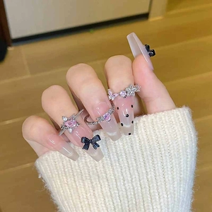 Adjustable silver rings set with pink heart and butterfly motifs worn on a white sweater