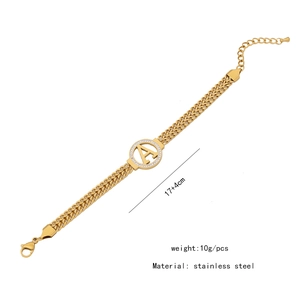 Macro detail of golden stainless steel bracelet with sparkling rhinestone letter A pendant