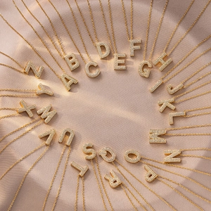 Golden 26 initial letter necklaces with zircon pendant on beige silk background