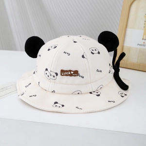 Détail d'un chapeau bébé avec oreilles de panda, décoration de nœud et étiquette Luck