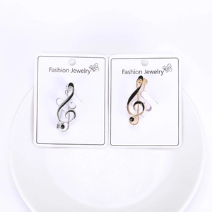 Detailed view of silver and gold treble clef music note brooches with sparkling rhinestones