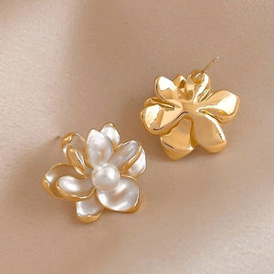 Elegant gold flower earrings with white pearls displayed on soft beige silk background