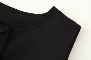 Close-up of crew neck detailing with single-breasted buttons on a black dress