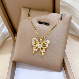 Detailed view of gold butterfly pendant with hollow zircon wings and heart crystal