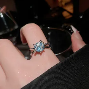 Crisscross sterling silver ring featuring a sparkling blue gemstone and zircon accents