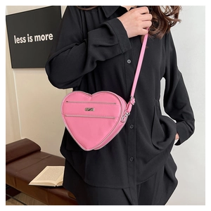 Lifestyle view of pink heart-shaped bag with dual zippers and adjustable strap on a model