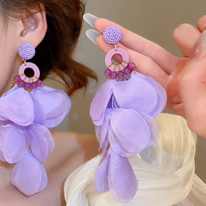 Detail of purple fabric flower tassel earrings with woven beads and golden metal rings