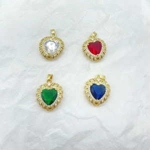 Gold plated heart pendants with colorful zircon crystals on a minimalist background