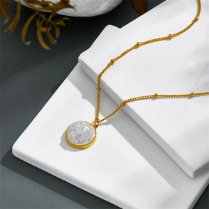 Vintage gold necklace with baroque pearl pendant on a geometric stone display