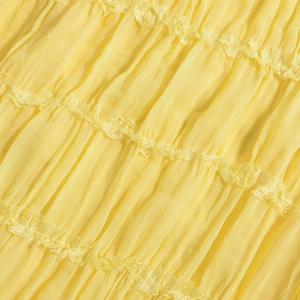 Detail of yellow pleated fabric with delicate lace trim on a backless summer dress