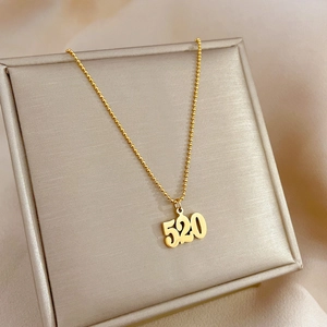 Detailed close-up of 520 number pendant on golden bead chain in a luxury jewelry box