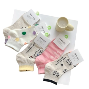 Chaussettes en coton à motifs pastels disposées à plat sur une surface blanche unie