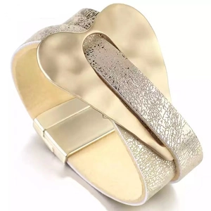 Fashionable gold magnetic leather cuff bracelet with heart charm on white background