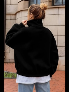 Outdoor back view of a minimalist black oversized sweatshirt featuring a wide lapel collar