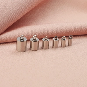 Set of six silver cylindrical pendant clasps for DIY jewelry making on pink fabric