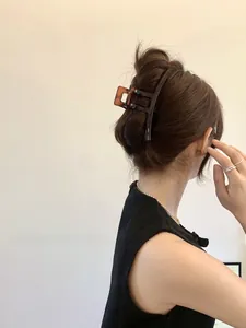 Elegant brunette model wearing a large amber-colored translucent hair claw clip for hair buns