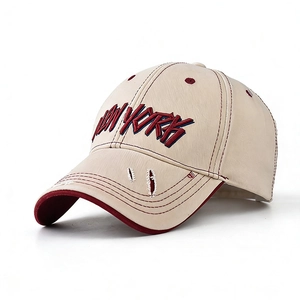 Close-up of NEW YORK embroidery and distressed brim on beige cotton baseball cap
