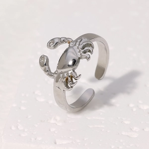 Vue détaillée d'une bague crabe en acier poli sur un support en pierre blanche