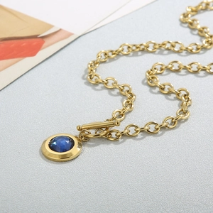 Gold OT clasp necklace with blue crystal pendant on a textured grey background