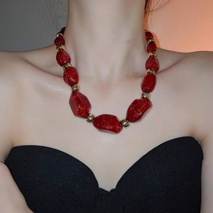 Close-up of chunky red acrylic beads with gold metallic spacers on a model's neck