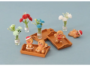 Miniature Christmas gingerbread men with tiny glass hope flower vases on brown trays