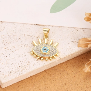Detailed close-up of a gold-plated evil eye pendant with blue zircon stones on a stone base
