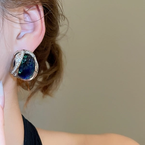 Gros plan de boucles d'oreilles géométriques vintage avec pierres irisées sur un modèle