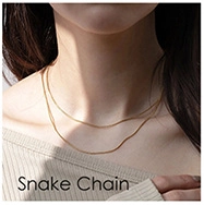 Gros plan d'un collier chaîne serpent dorée minimaliste porté par un mannequin pour l'élégance