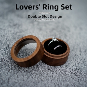 Detail of round walnut wood ring box with dual slots and black velvet lining