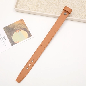 Detailed view of a brown leather wrist strap with adjustable holes on a white desk