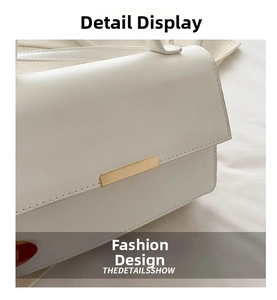 Detailed macro view of white leather bag featuring a sleek gold metal decorative element