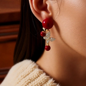 Détail de boucles d'oreilles papillon en or 18 carats avec perles rouges et cristaux