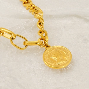 Vue macro d'une chaîne cubaine dorée avec détail du pendentif pièce Reine Elizabeth