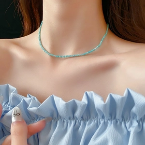 Gros plan d'un collier de perles bleu clair porté par un mannequin au style bohème
