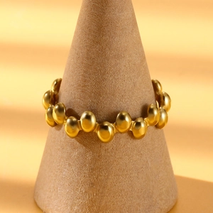 Detailed view of a golden stainless steel beaded ring on a cone-shaped display