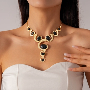 Détail d'un collier gothique géométrique avec spirales dorées et gemmes ovales noires