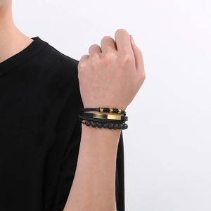 Close-up of men's multilayer braided leather bracelet with volcanic stone and gold accents