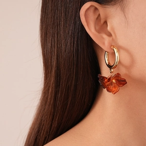 Gros plan d'une femme portant des boucles d'oreilles fleur en acrylique et cerceau doré