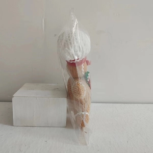 Side view of gingerbread man knit plush toy with chef hat in transparent plastic bag