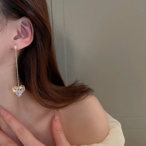 Dettaglio di orecchini a nappa dorata con pendenti a cuore in zircone su una modella