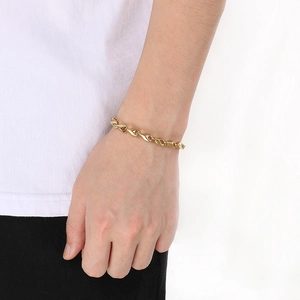 Makro-Detail eines goldenen Edelstahl-Rautenarmbands an einem männlichen Handgelenk