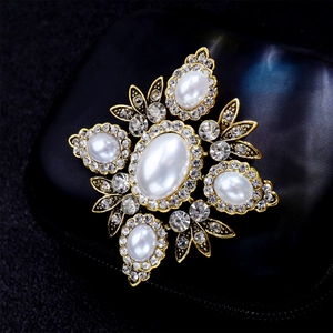 Macro shot of a vintage gold cross brooch featuring large pearls and sparkling rhinestones