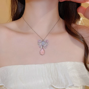Close-up of butterfly pendant necklace with pink teardrop crystal on model neck