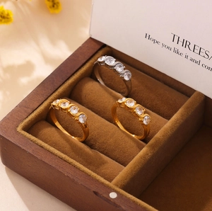 Three minimalist stainless steel rings set with rows of cubic zirconia in a jewelry box