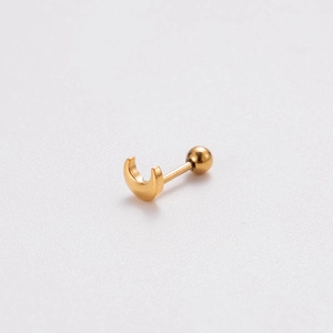 Detail of golden crescent moon stud earring with round ball back on textured background