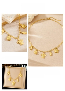 Detailed macro view of gold sea charms and paperclip chain necklace in a gift box