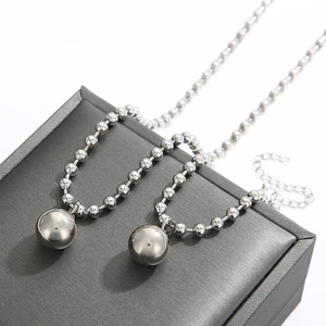 Detail view of double-layer silver bead chain necklace on a gray jewelry box